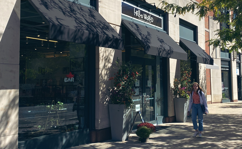 person walking in front of a store front on a sunny day