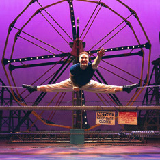 cirque performer doing a split on a tightrpe