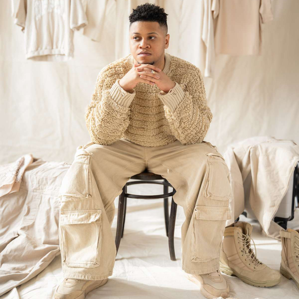african-american man in beige sweater and jeans sitting in front of a beige background