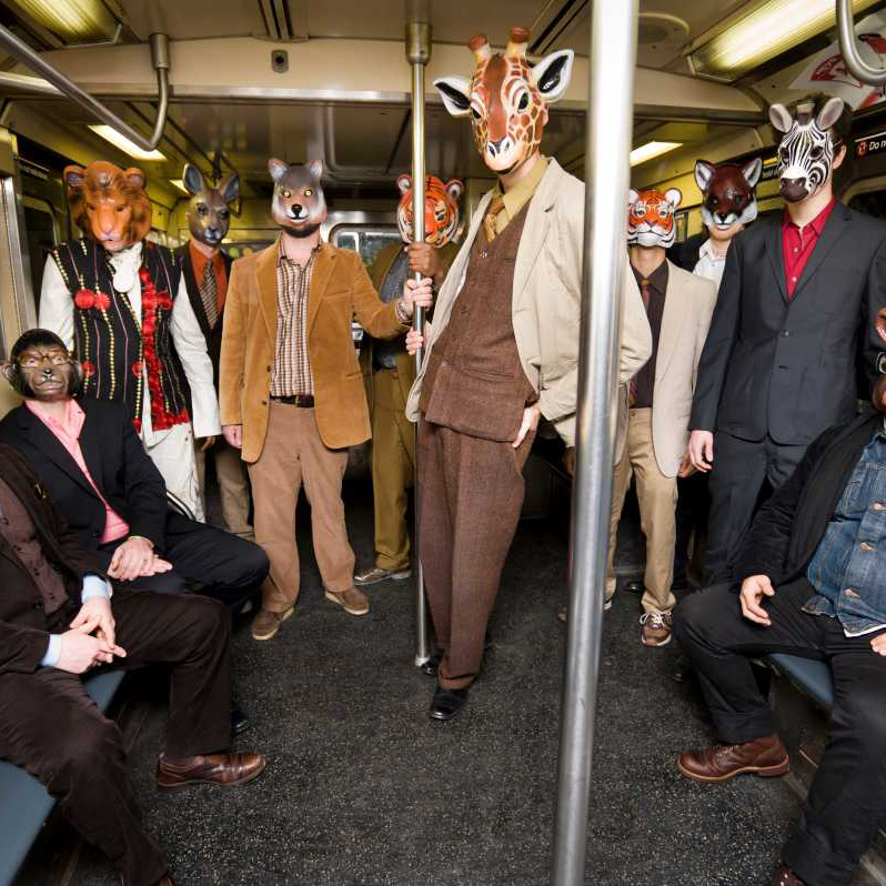 men in suits and animal masks riding in a subway car