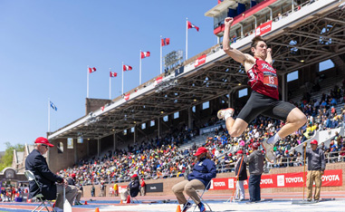 long jumper in the air with a stadium crowd watching