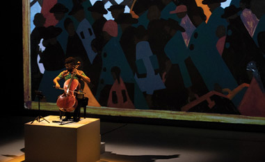 man performing cello in front of stain glass display