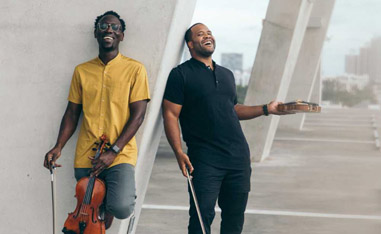 two men standing with violins