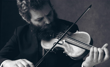 black and white photo of bearded man playing violin