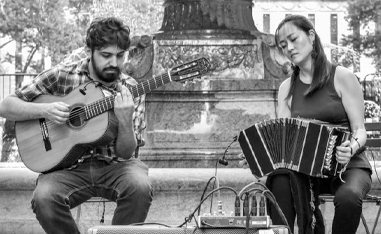 black and white photo of a man and a woman sitting and playing instruments