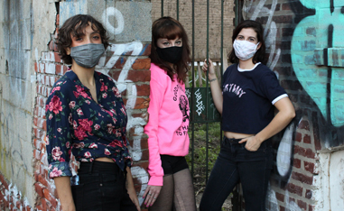 three girls standing in front of concrete wall