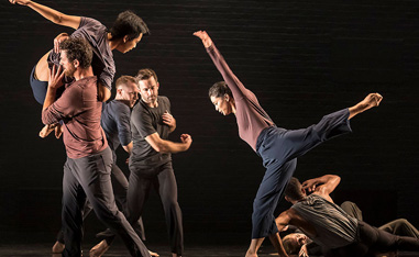 dancers performing on stage in front of a black background