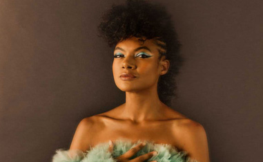 african-american woman in green dress standing in front of a gray wall