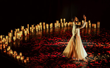 man performing on stage surrounded by candles