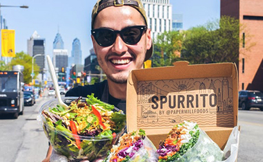 Man outside holding burrito bowl and spring roll burrito