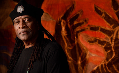 black man in beret in front of red background