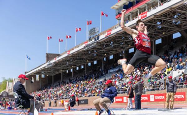 man doing long jump in front of stadium crowd