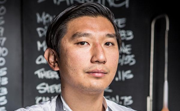 asian man's head and shoulders in front of chalkboard
