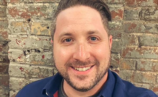 smiling man in front of brick wall