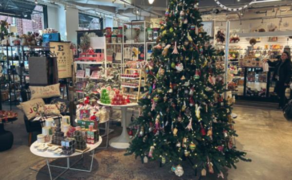 christmas tree with ornaments and a table of christmas items in a store