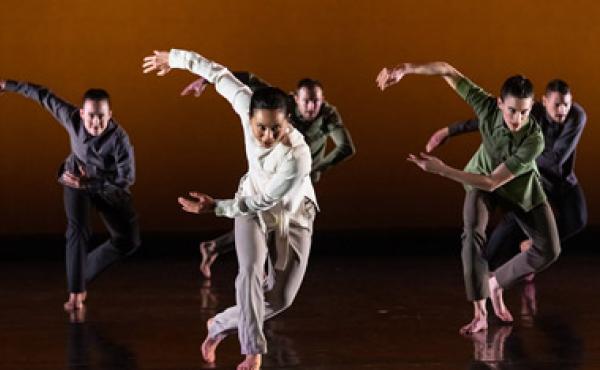 dancers performing in front of orange background