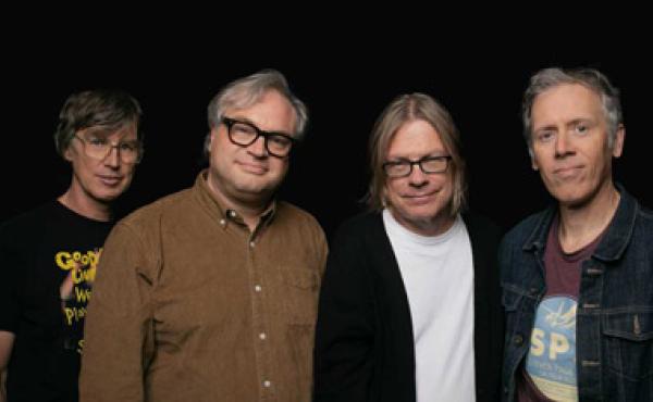 four men standing in front of a black background
