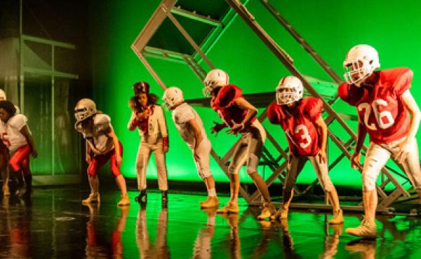 dancers in football uniforms on stage in front of green background