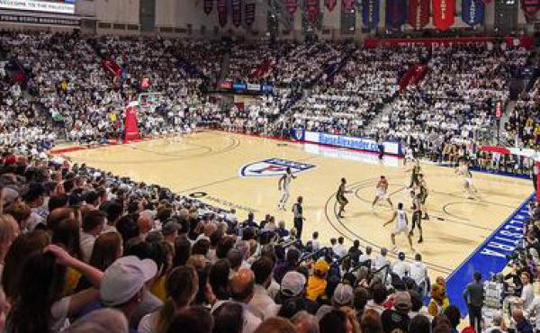 two teams playing basketball in front of a full stadium