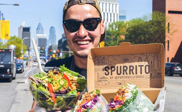 man outside holding burrito bowl and spring roll burrito