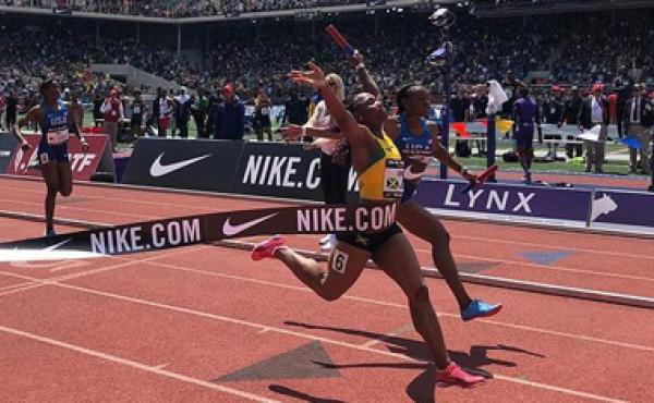 woman raising arms as she runs across finish line