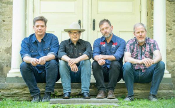 four men sitting on a stoop in a line