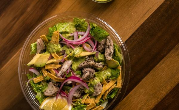 Salad with steak and onions on wooden table in glass bowl