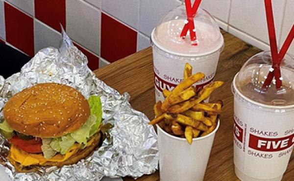 a cheeseburger, cup of fries and two milkshakes on a table