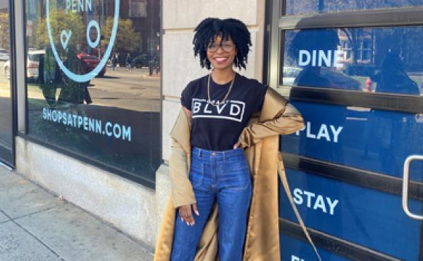 black woman posing in front of a shop door