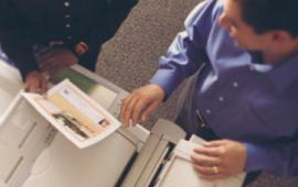 Two individuals making copies inside the UPS Store.